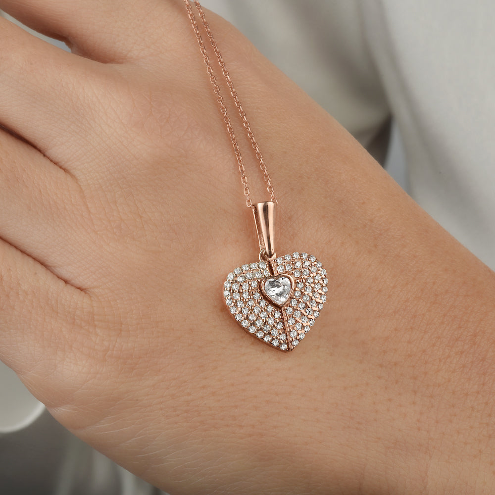 Secret Heart Kette in Rosé mit Herzanhänger, getragen auf der Hand.