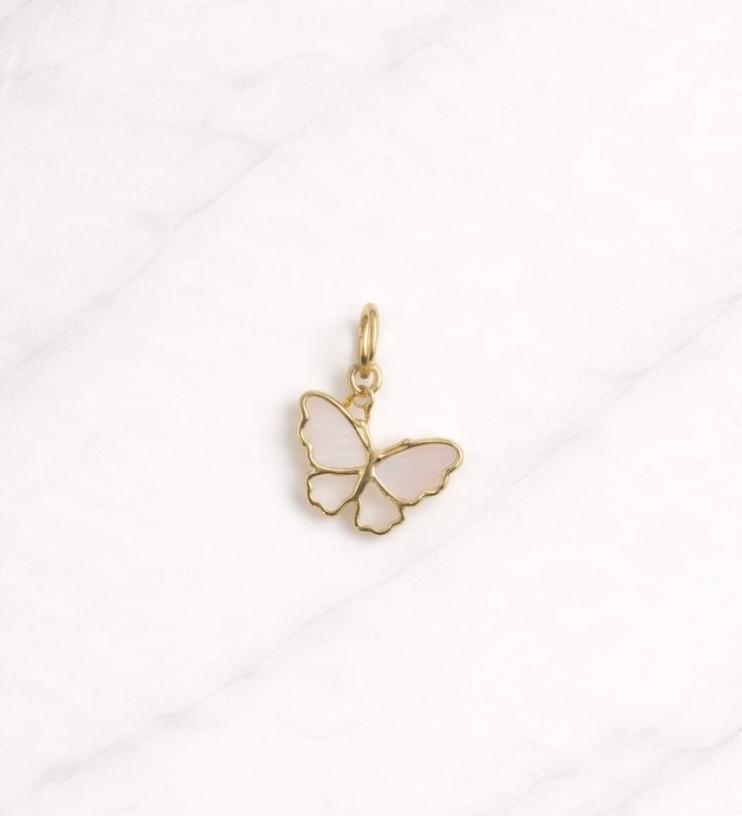 Seville CHARM Schmetterling in Gold mit hellen Flügel-Details auf hellem Marmorhintergrund.