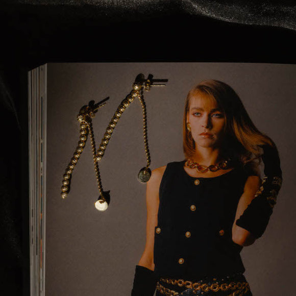 Lifestyle: SHINY BALLS II Ohrringe Gold auf Magazin, stilvolle Schmuckaufnahme mit glänzenden Kugeln.