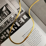 Sleek Halskette Gold Flatlay auf Magazin/Book, glänzende flache Kette.