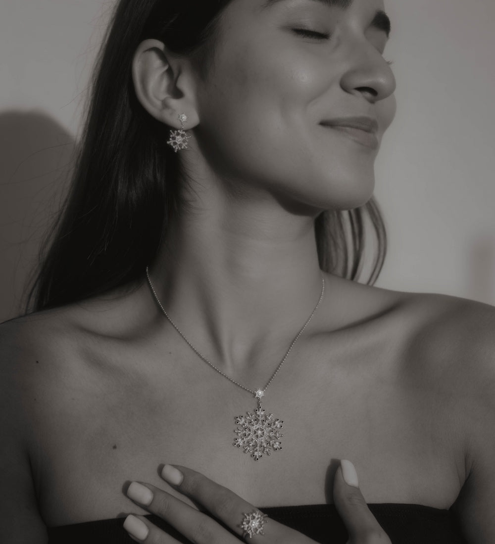 Frau trägt Snowflake Ice Halskette, Ohrringe und Ring in Silber mit funkelnder Schneeflocke.