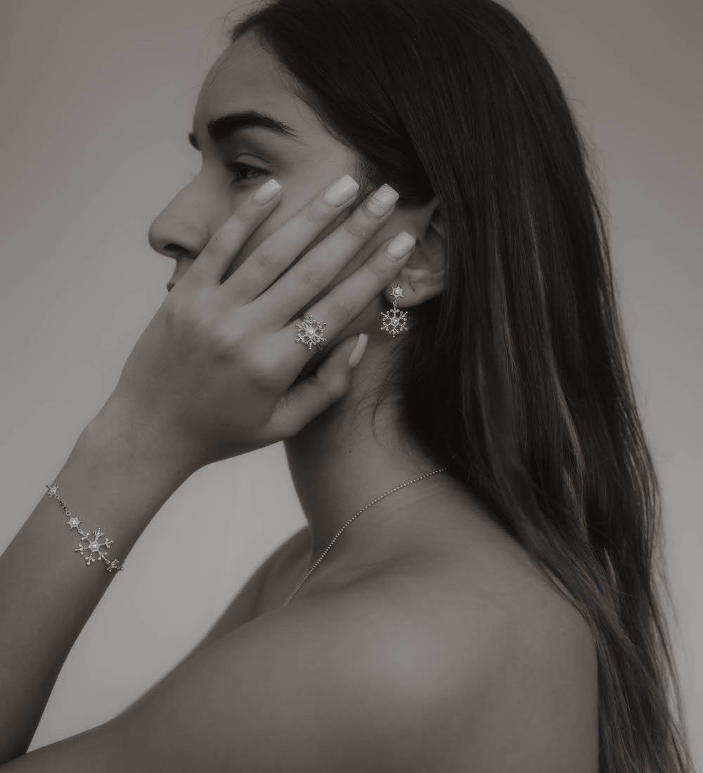 Snowflake Ice X Armkette Silber am Handgelenk einer Frau, kombiniert mit passendem Schmuck.