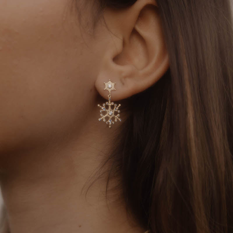 Ohrring am Ohr getragen – Snowflake Ice X Stecker in Goldoptik mit funkelndem Schneeflocken-Anhänger.