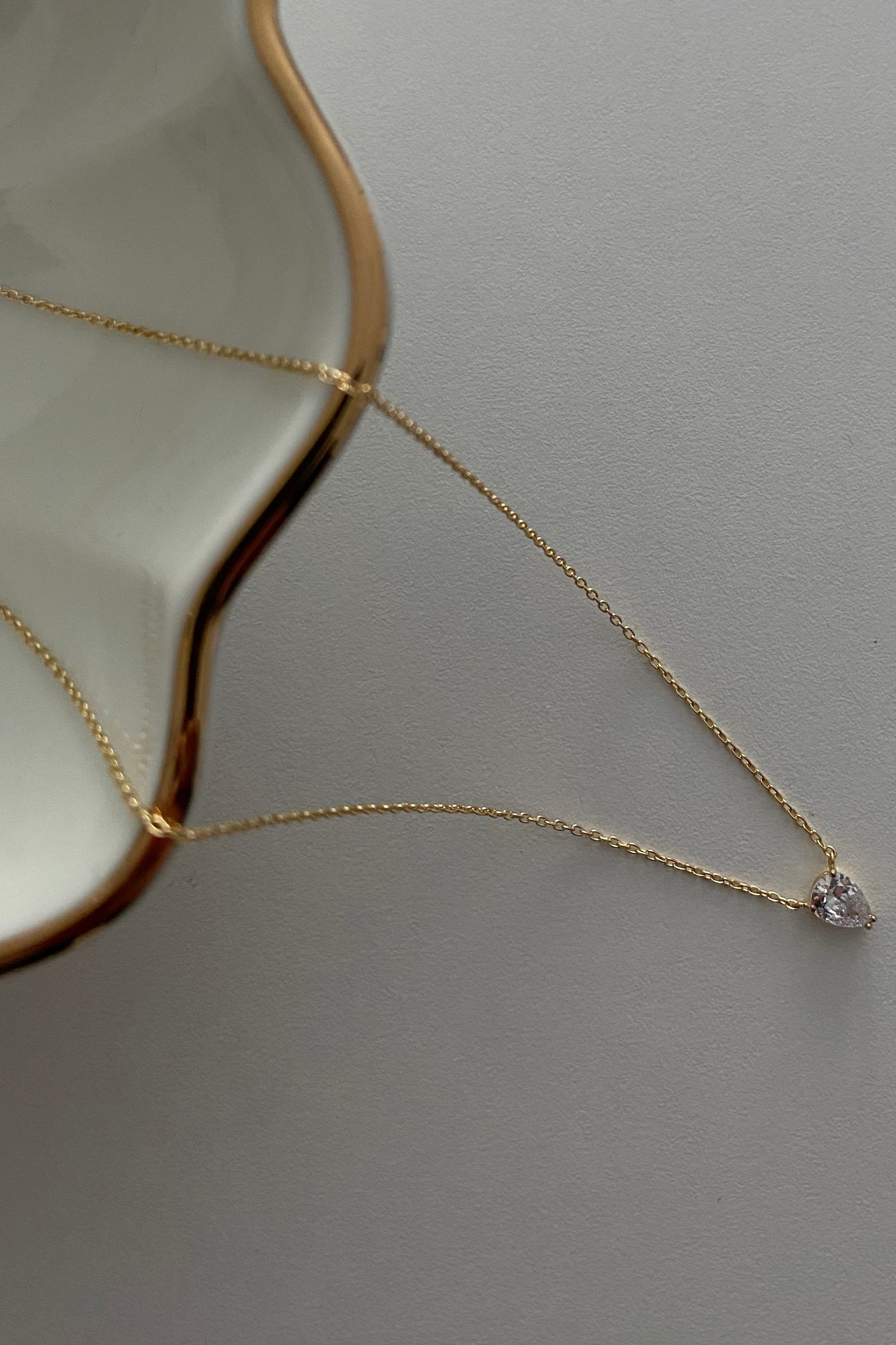 Zirkonia-Tropfen Anhänger an feiner goldener Kette – Solitär Drop Chain auf hellem Untergrund.