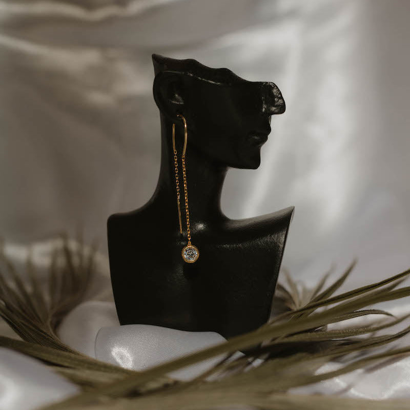 Einzelner Solitär Ohrring Gold an schwarzer Büste, langer Hänger mit Zirkonia.