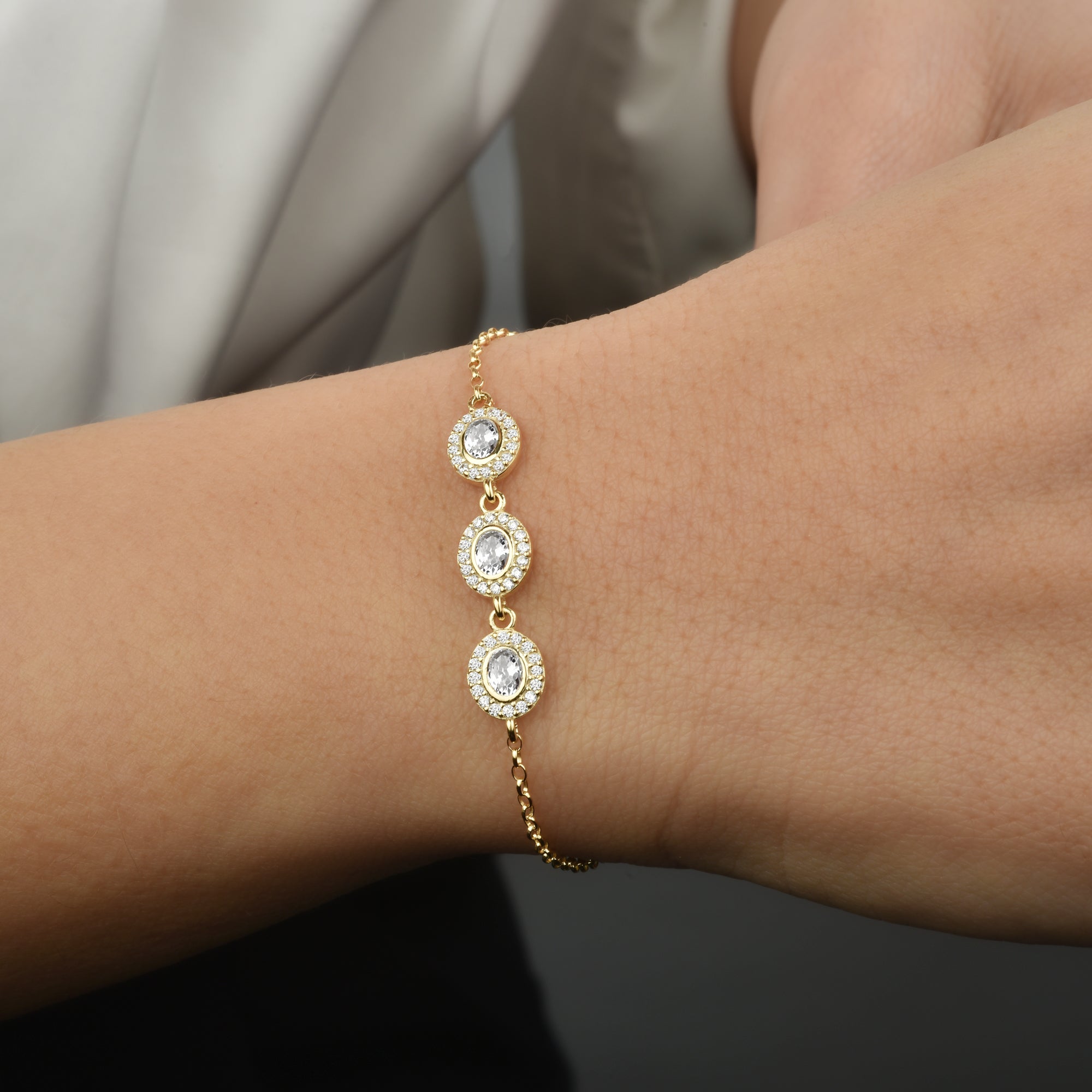 Goldenes Solitaire Kranz Oval Armband am Handgelenk, drei ovale Zirkonia mit funkelndem Kristallkranz.