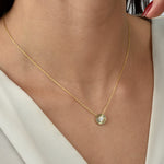 Goldene Solitaire Sun Halskette mit kleinem Sonnen-Anhänger und Zirkonia am Hals einer Frau.