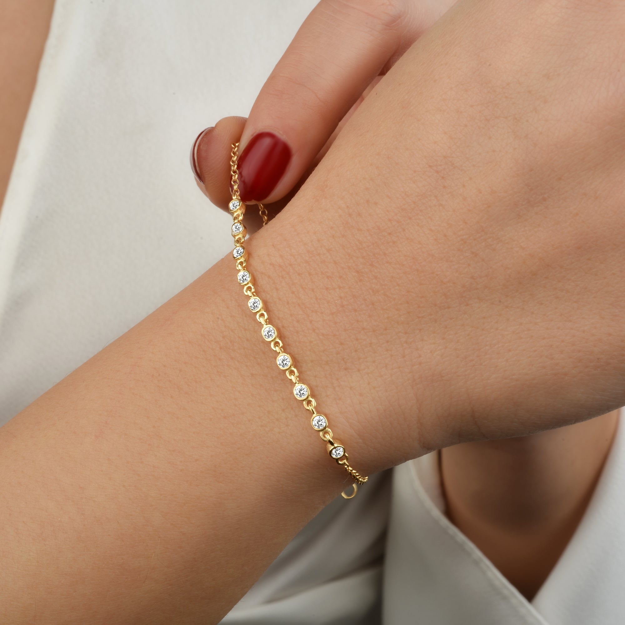 Nahaufnahme Sparkle Zirkonia Goldarmband am Handgelenk einer Frau in weißer Bluse.