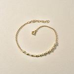 Filigranes Sparkle Zirkonia Armband Gold flach liegend auf beigem Untergrund.