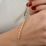 Frau hält funkelndes Sparkle Zirkonia Armband Gold locker über ihrem Handgelenk.