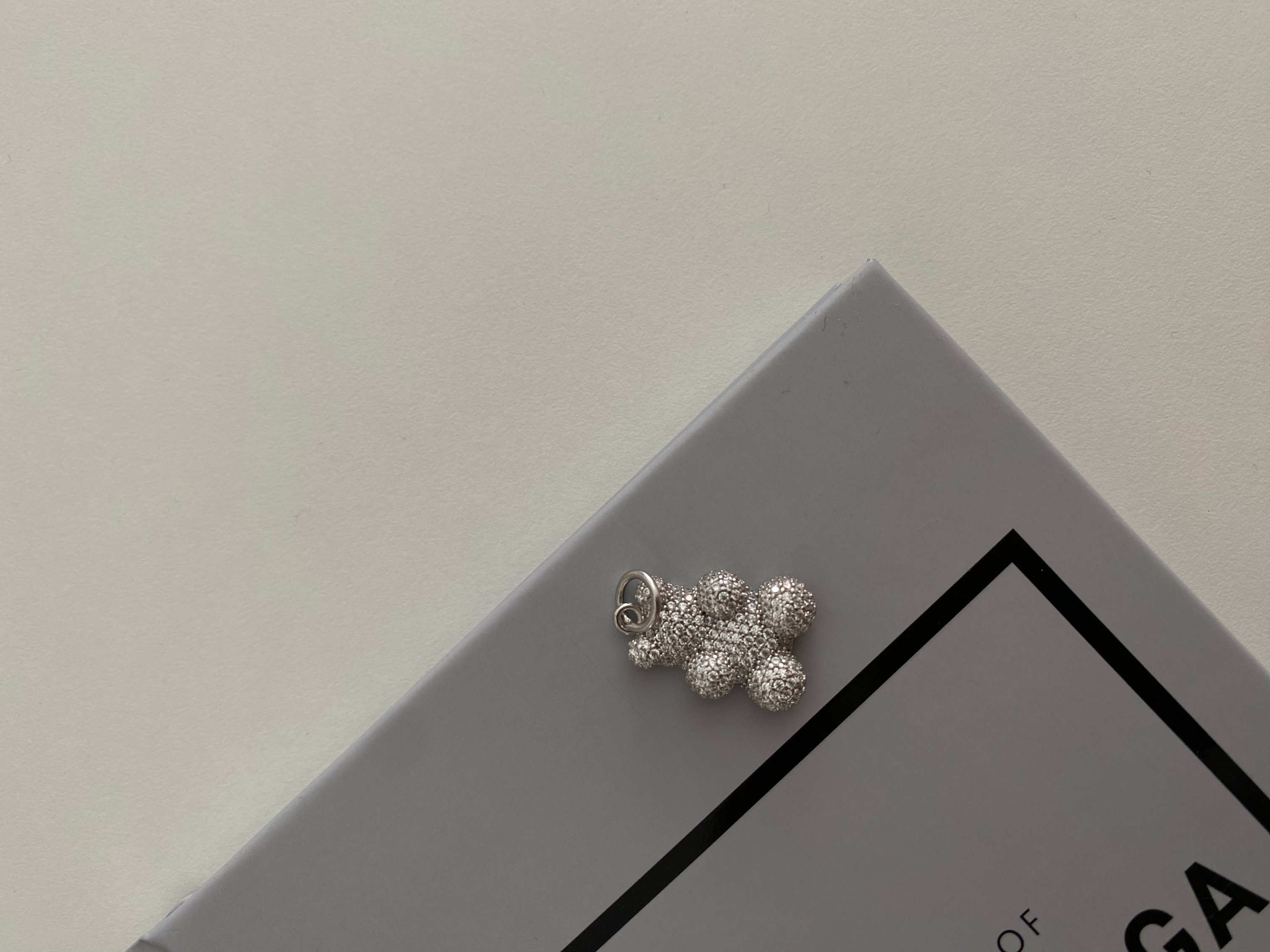 Sparkling Bear Anhänger aus 925 Sterling Silber mit Zirkonia auf grauem Buch-Cover.