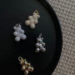 Vier Sparkling Bear Anhänger in Silber, Gold und glänzendem Metall auf schwarzem Teller.