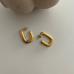 Goldene Square Hoop Ohrringe auf hellem Untergrund, modernes minimalistisches Styling.