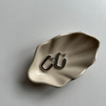 Silberne Square Hoop Ohrringe auf beiger Schmuckschale, minimalistisches Flatlay.