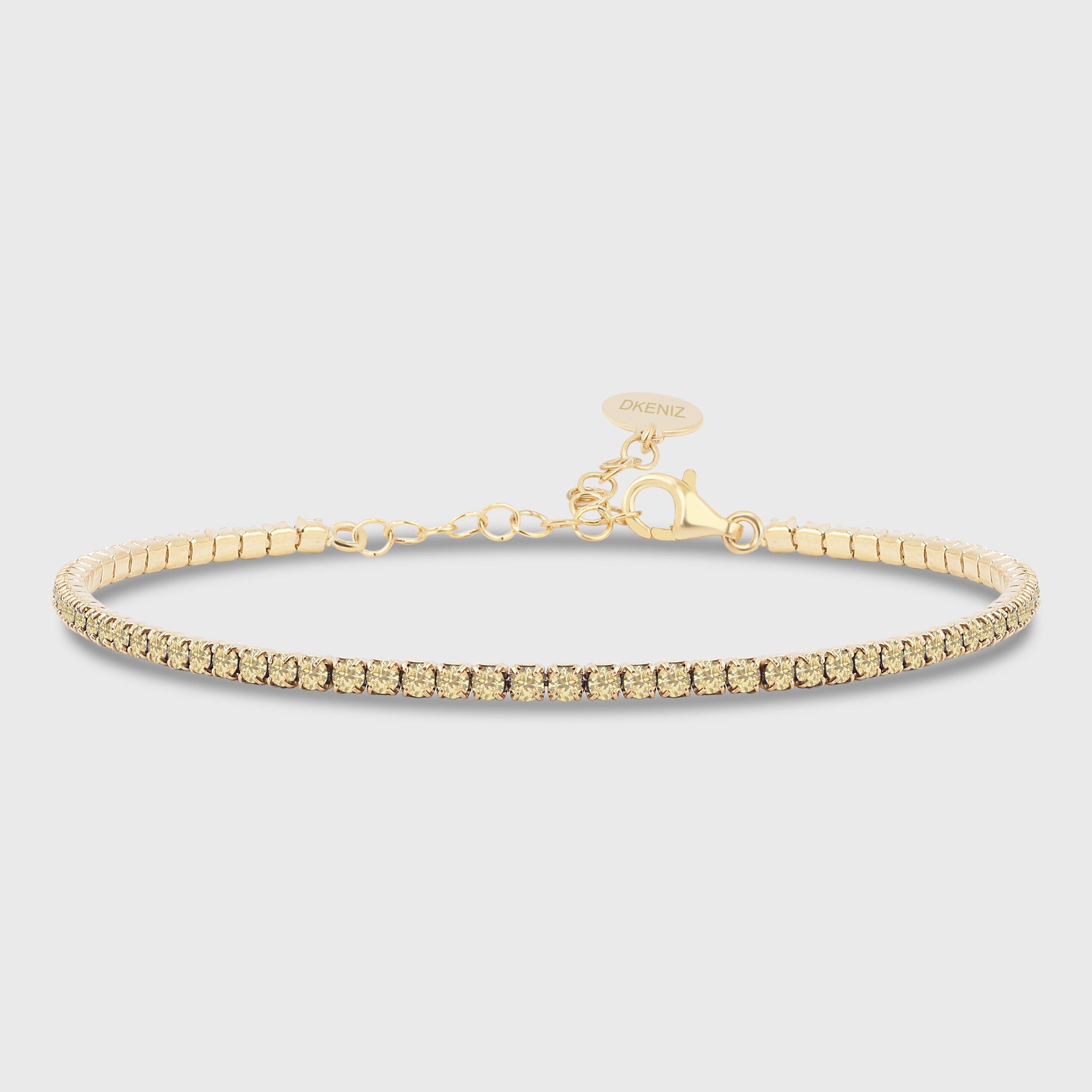Tennis Armkette Citrin Mini in Gold mit gelben Zirkonia-Steinen auf hellem Hintergrund.