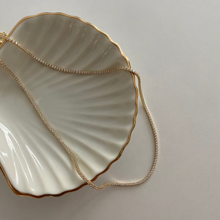 Goldene Tennis Kette Mini auf Schmuckschale – minimalistischer Zirkonia Schmuck in Gold-Optik.