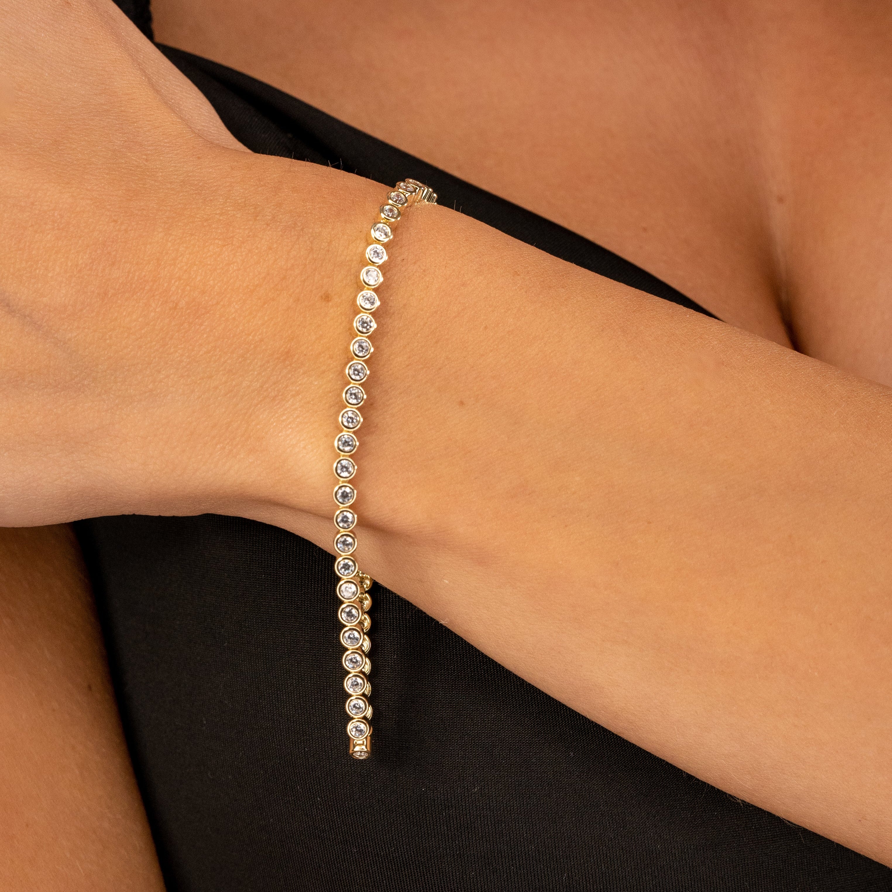 Tennisarmband Gold am Handgelenk getragen – eleganter Zirkonia Glanz für Damen.