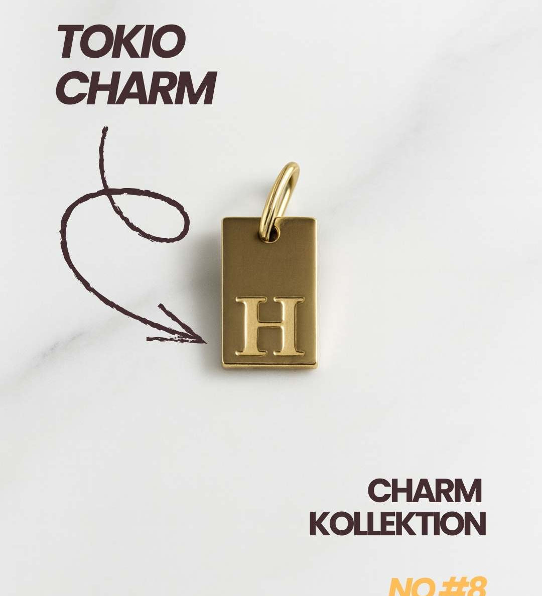 Detailaufnahme des goldenen Tokio Initial Anhängers mit Buchstabenprägung