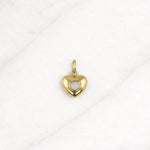 Tulum Charm in Gold mit Herzform und weißem Stein auf hellem Hintergrund.