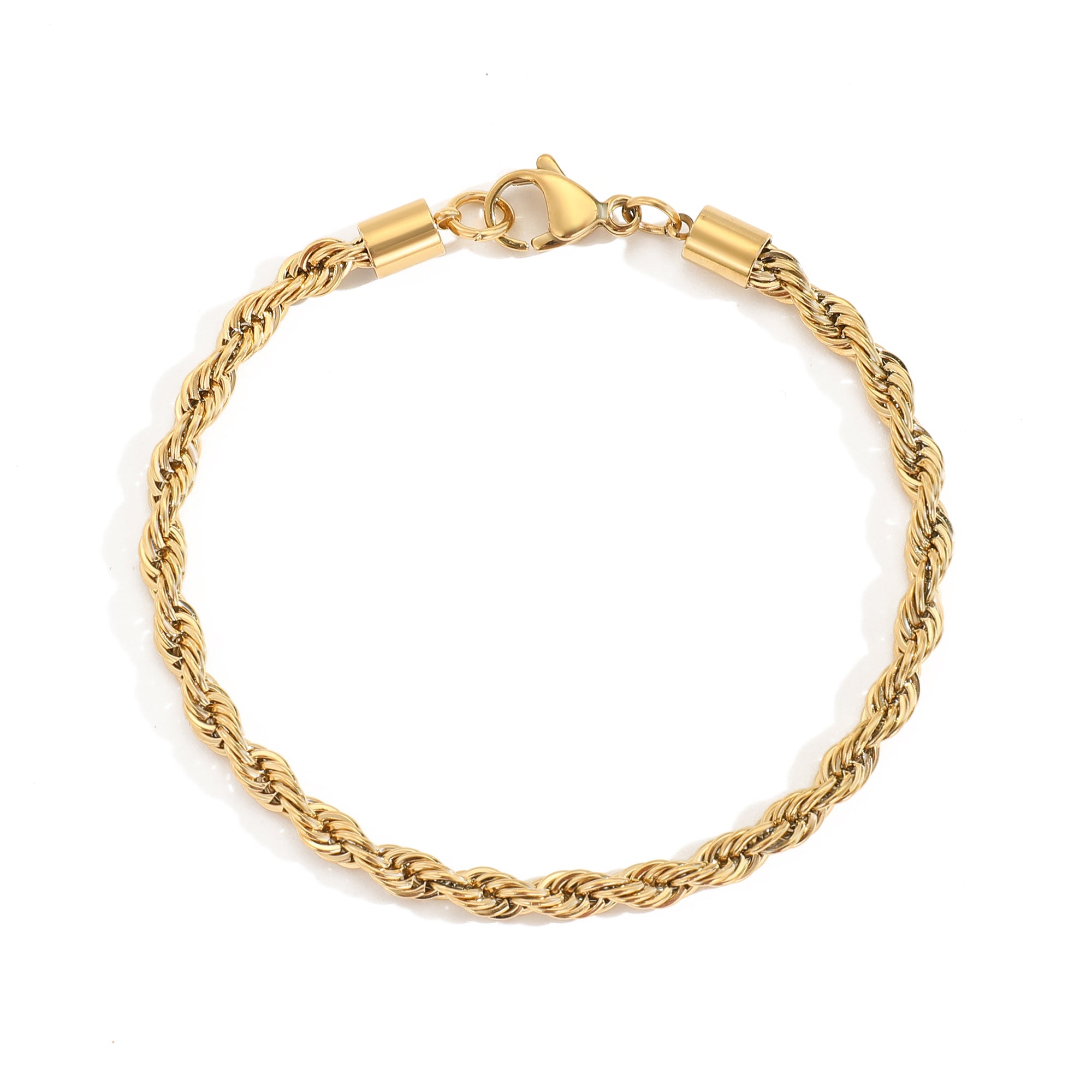 Goldenes Twist Armband aus Edelstahl neben flacher Kette auf hellem Untergrund.