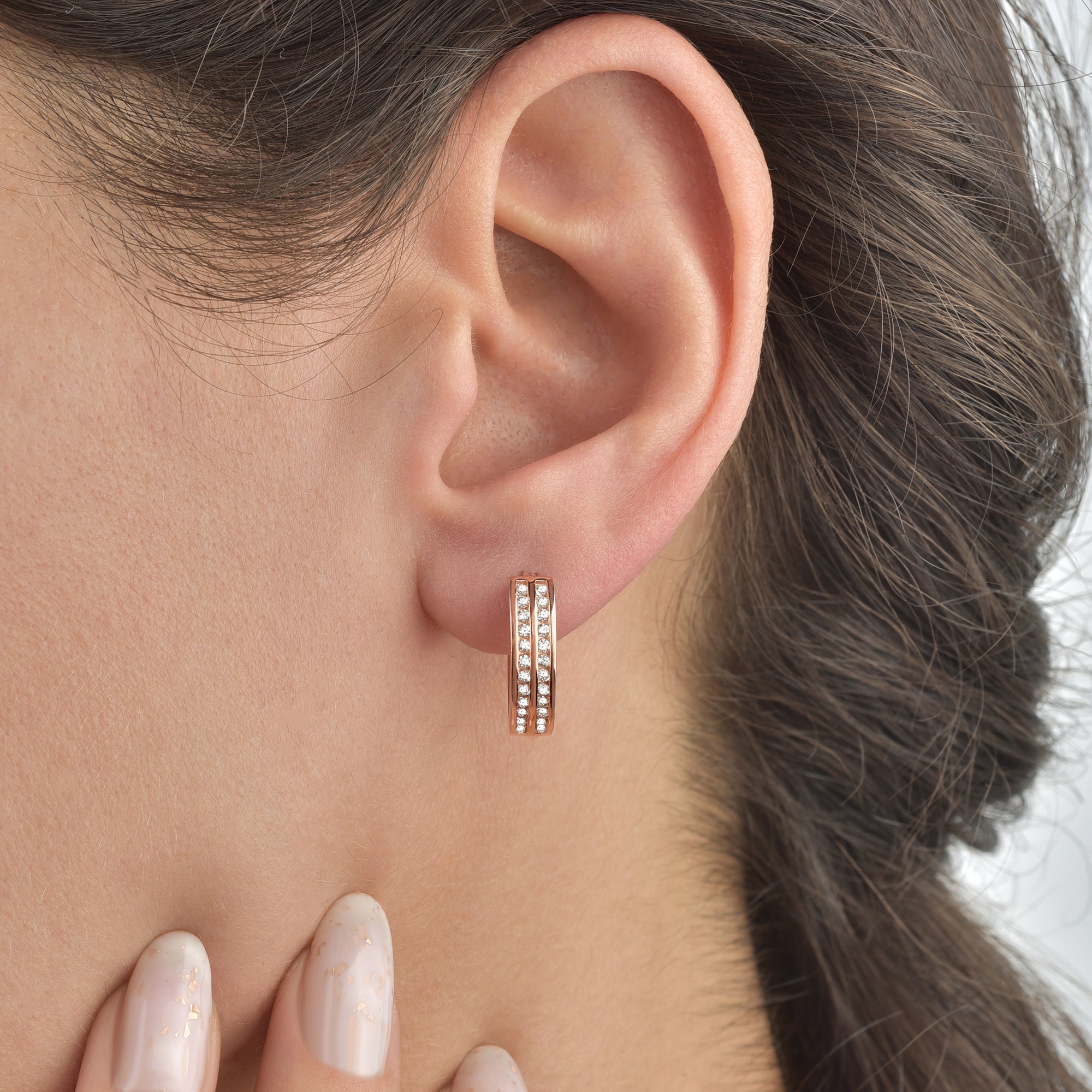 Two Line Zirkonia Creolen in Rosé am Ohr einer Frau, eleganter Alltagslook.