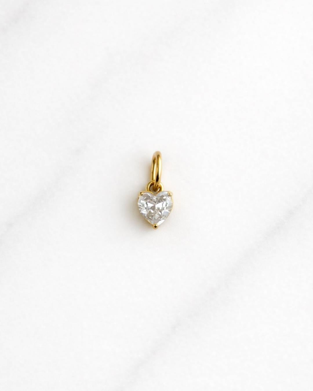 Venice CHARM Gold Herzanhänger mit funkelndem Kristall für Damen auf hellem Marmorhintergrund.