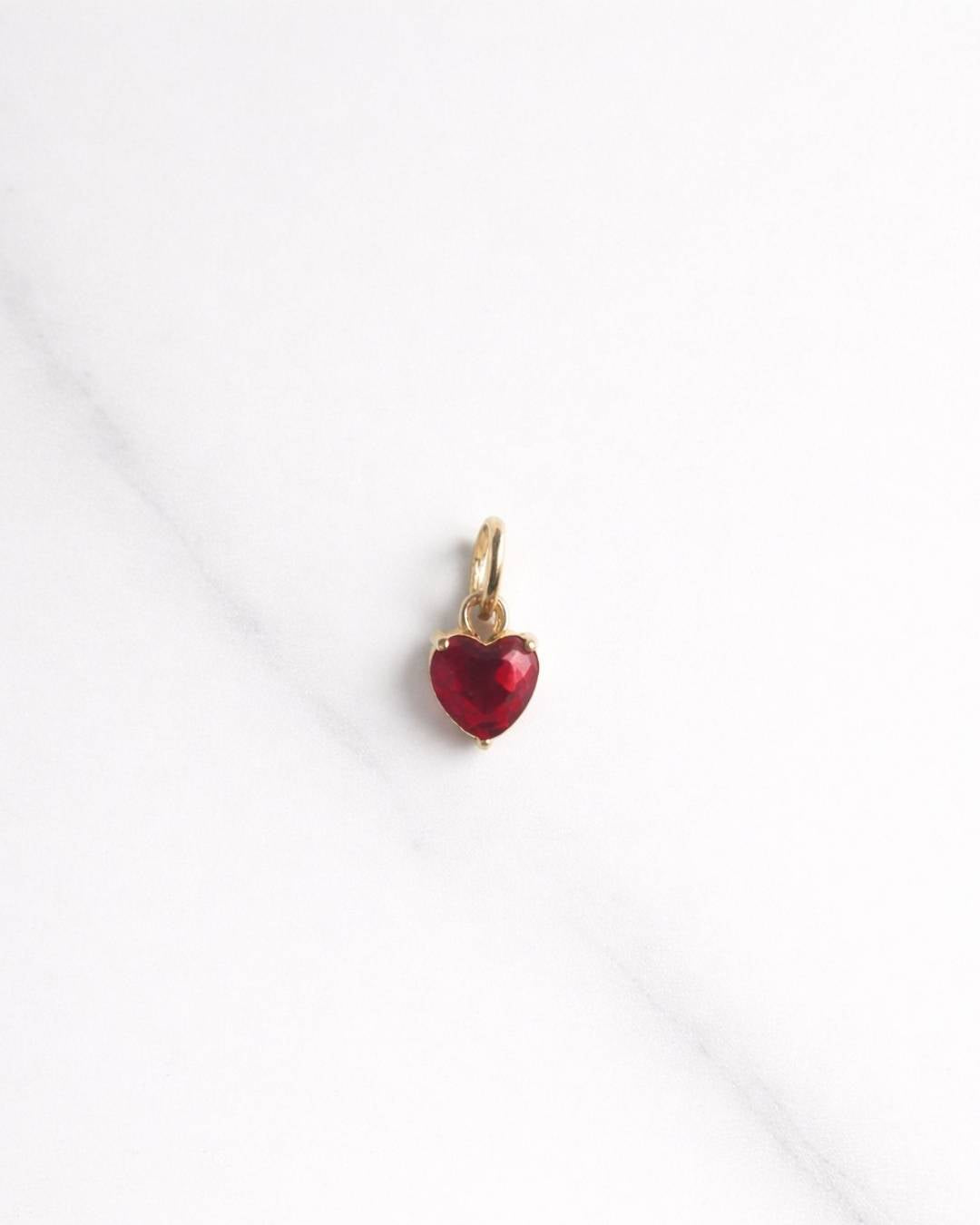 Verona Charm in Gold mit rotem Herzstein auf hellem Hintergrund – kleiner Anhänger für Kette oder Armband.