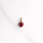 Verona Charm in Gold mit rotem Herzstein auf hellem Hintergrund – kleiner Anhänger für Kette oder Armband.