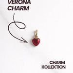 Produktbild Verona Charm: goldener Herz-Charm mit rotem Stein, Schriftzug „Verona Charm“ und Pfeil.