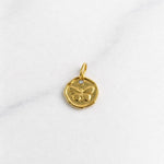 Vienna Charm in Gold mit Schmetterling-Prägung und kleinem Stein auf hellem Hintergrund.