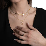Detailfoto: Notenschlüssel Halskette Gold mit Zirkonia, getragen zu schwarzem Outfit.