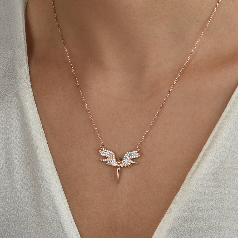 White Angle Kette – Rosé mit Engelsflügel-Anhänger am Hals einer Frau, elegantes Dekolleté.