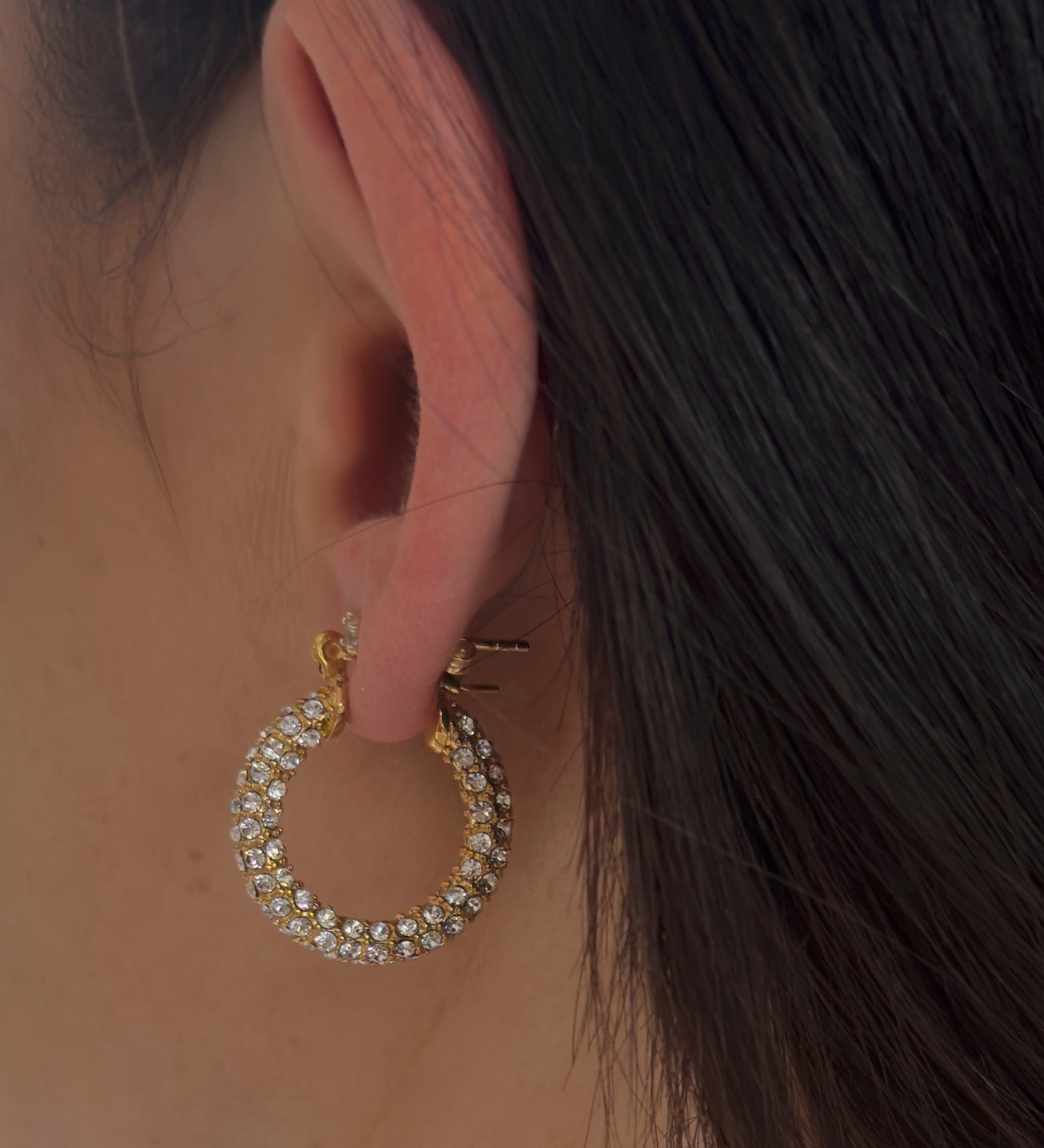 Detailansicht goldene Zirkonia-Huggie-Creole am Ohr, runde Pavé-Fassung, elegant und wasserfest.
