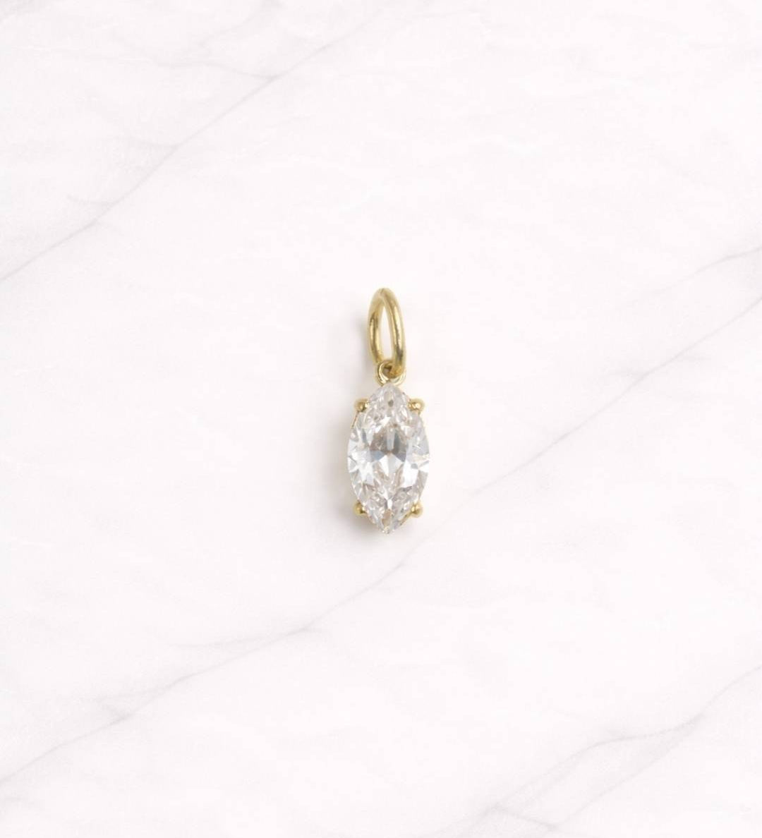 Zurich CHARM in Gold mit klarem Marquise-Zirkonia auf hellem Marmorhintergrund.