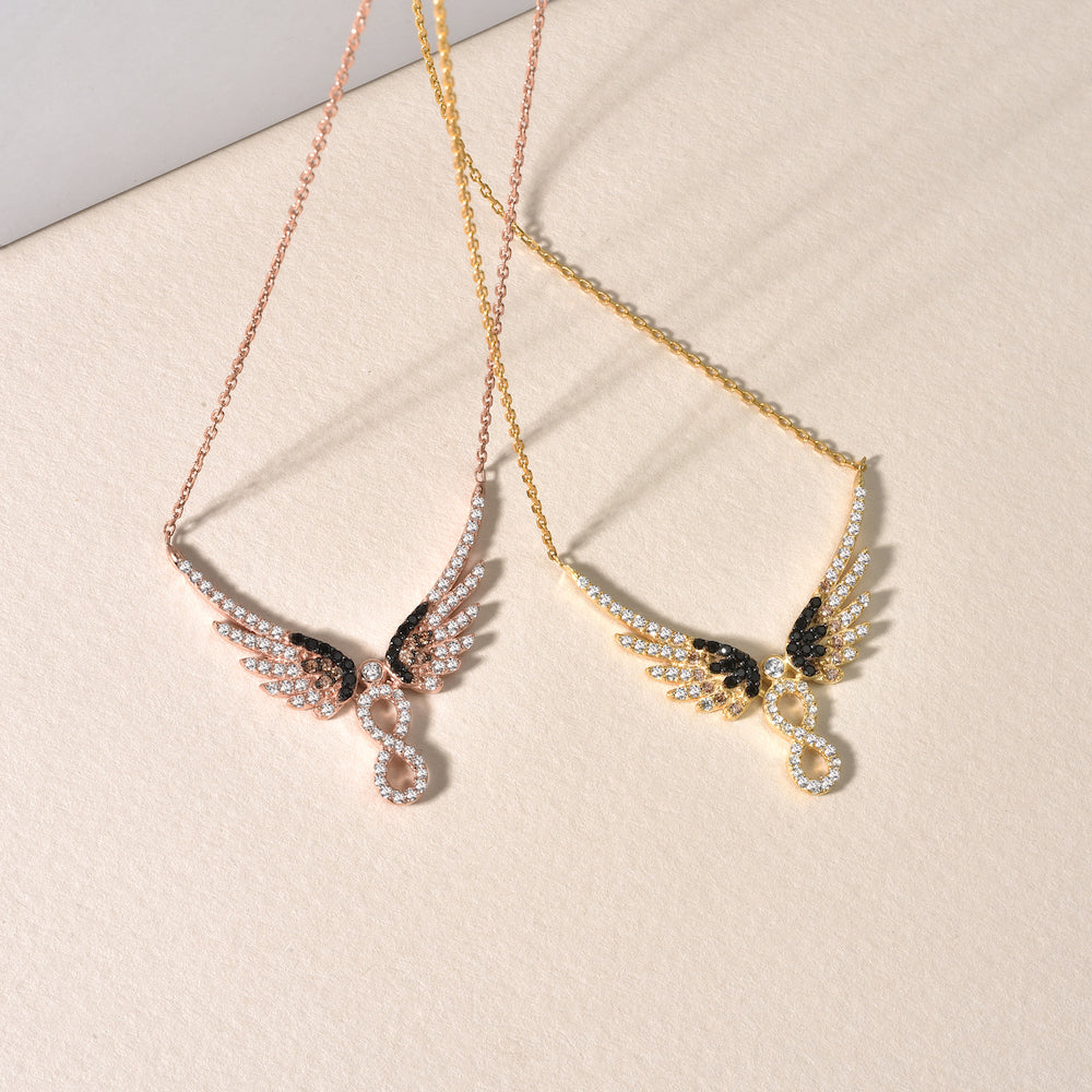 Rosé- und goldvergoldete Infinity Angel Wings Halsketten nebeneinander auf hellem Untergrund.