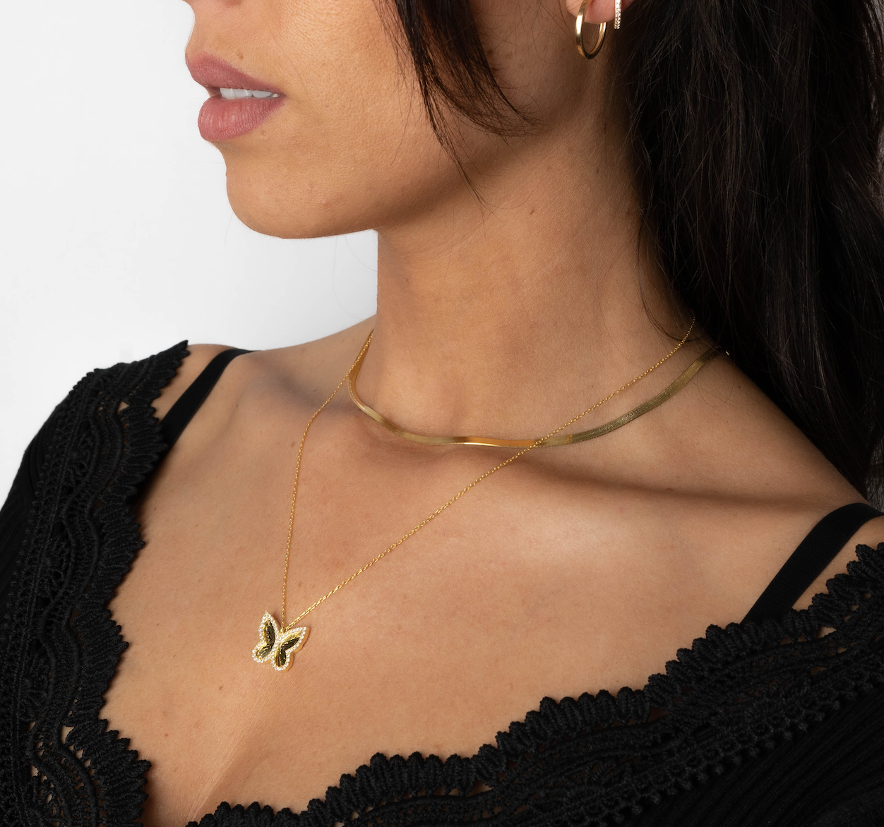 Model mit Butterfly Halskette und Gold-Choker, stilvoll geschichteter Halsketten-Look für Damen.
