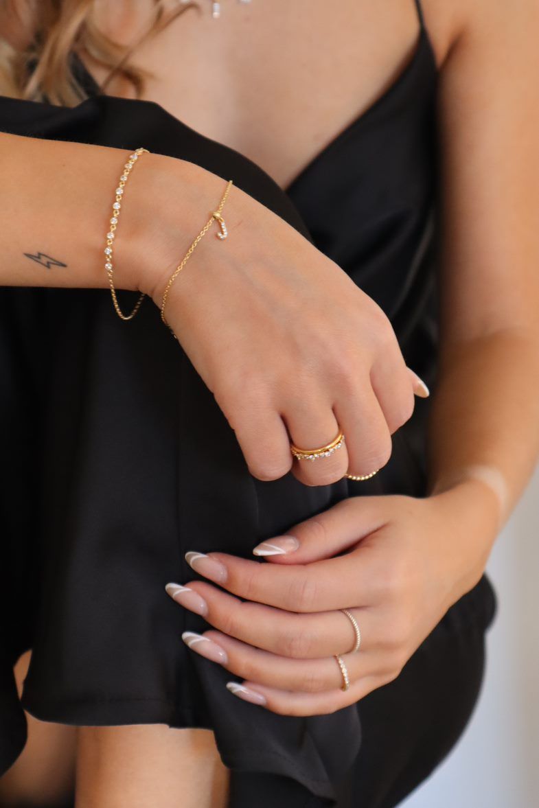 Hände mit goldenen Armbändern und Ringen, kombiniert mit Charm Numbers Schmuck.