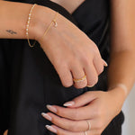 Hände mit goldenen Armbändern und Ringen, kombiniert mit Charm Numbers Schmuck.