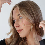 Modell mit goldener Halskette und mehreren Charm Numbers Ziffern im Gesicht.