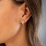 Creolen mit Zirkoniawelle in Gold am Ohr getragen – eleganter Look, funkelnde Zirkonia.