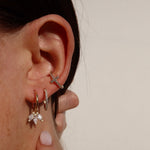 CROSS PAVE EAR CUFF mit Zirkonia am Ohr, kombiniert mit weiteren filigranen Creolen.