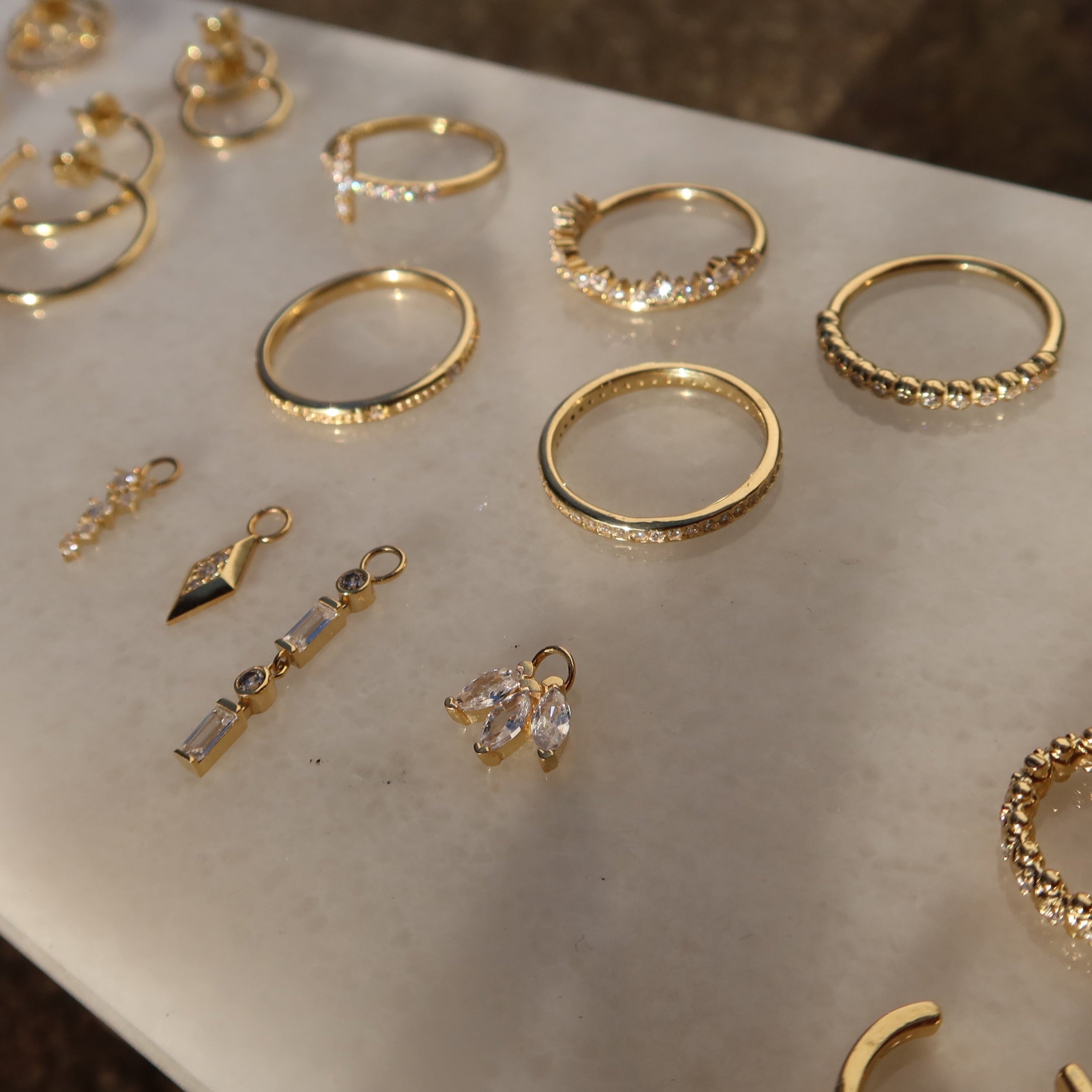 Flatlay Schmuck in Gold: Diadem Ring mit Zirkonia zusammen mit weiteren Ringen.