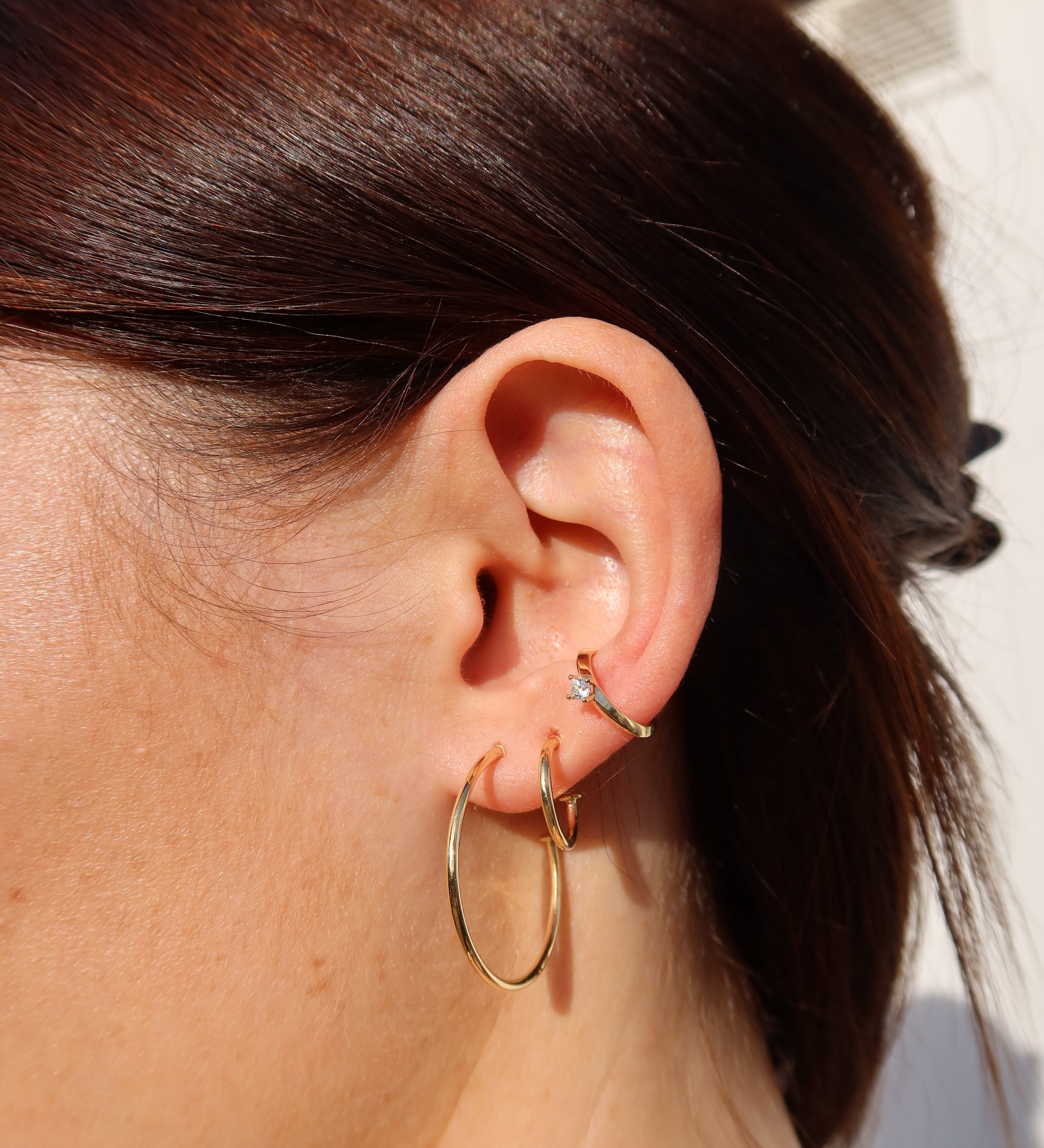 Kleine, schlanke Creolen am Ohr – eleganter Everyday-Schmuck in klassischem Design.