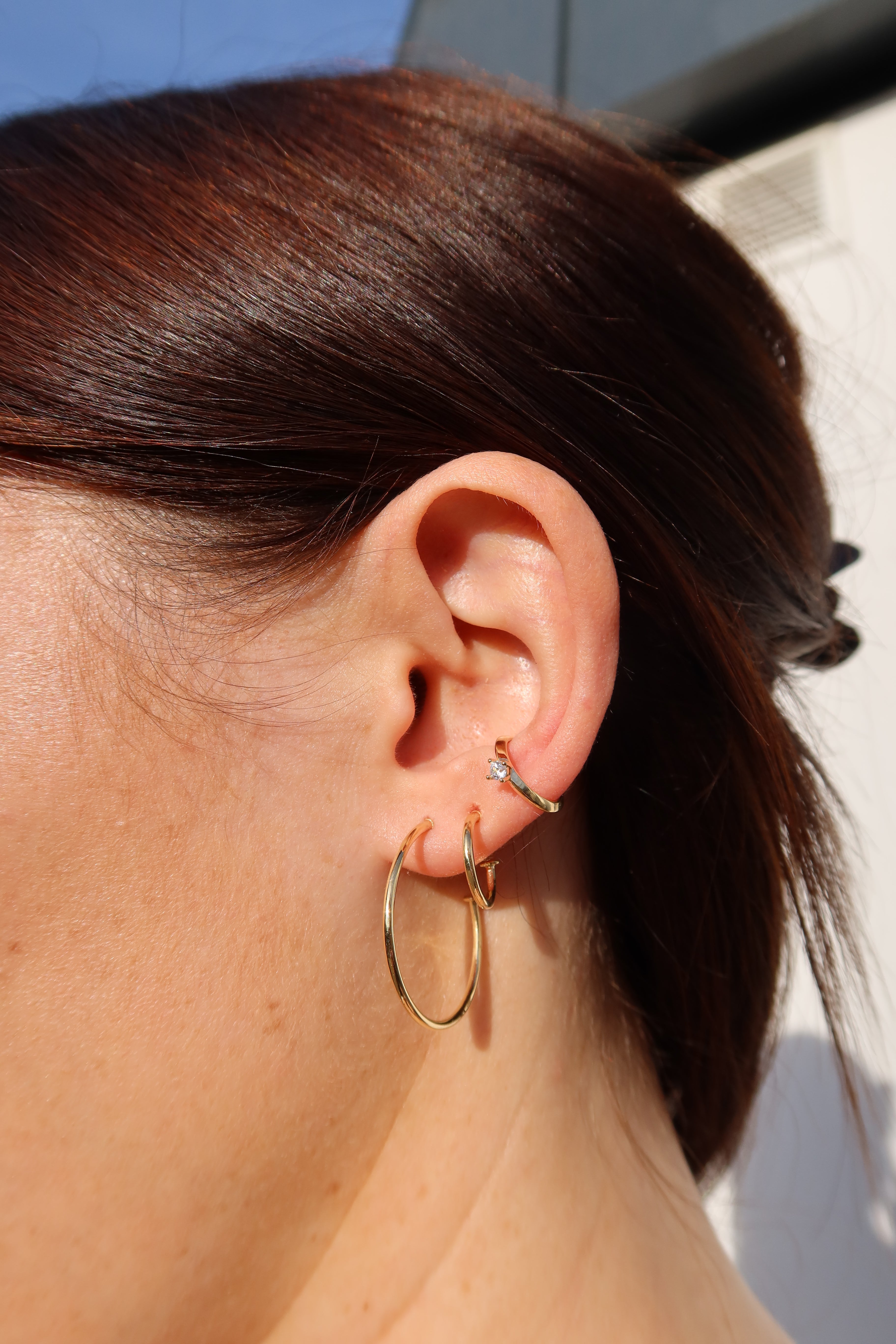 Kleine, schlanke Creolen am Ohr – eleganter Everyday-Schmuck in klassischem Design.