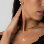 Model trägt goldfarbene Drops Halskette mit Zirkonia im Dekolleté.