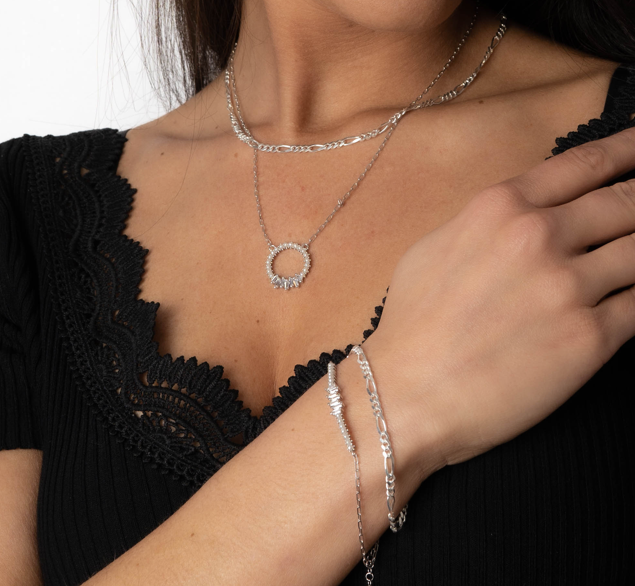 Layering-Look mit FIGARO Armkette und Halskette in Silber an Frau im schwarzen Oberteil.