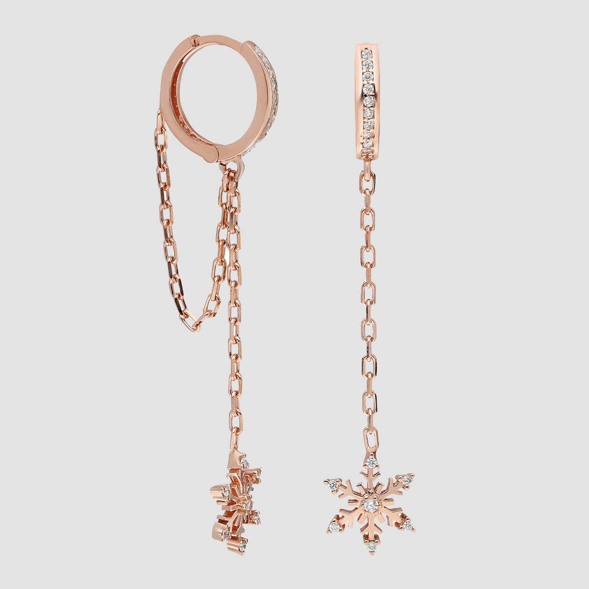 Rosévergoldete Hängecreolen mit Schneeflockenanhänger und Zirkonia in Kettenoptik vor hellem Hintergrund.