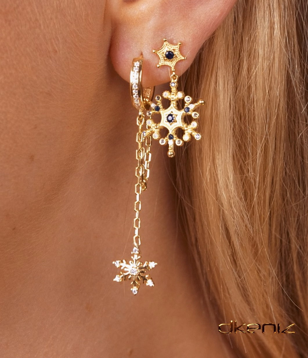 Ohr mit mehreren rosévergoldete Ohrringen, im Fokus Hängecreole mit Schneeflockenanhänger und Zirkonia-Steinen.