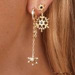 Ohr mit mehreren silberfarbenen  Ohrringen, im Fokus Hängecreole mit Schneeflockenanhänger und Zirkonia-Steinen.