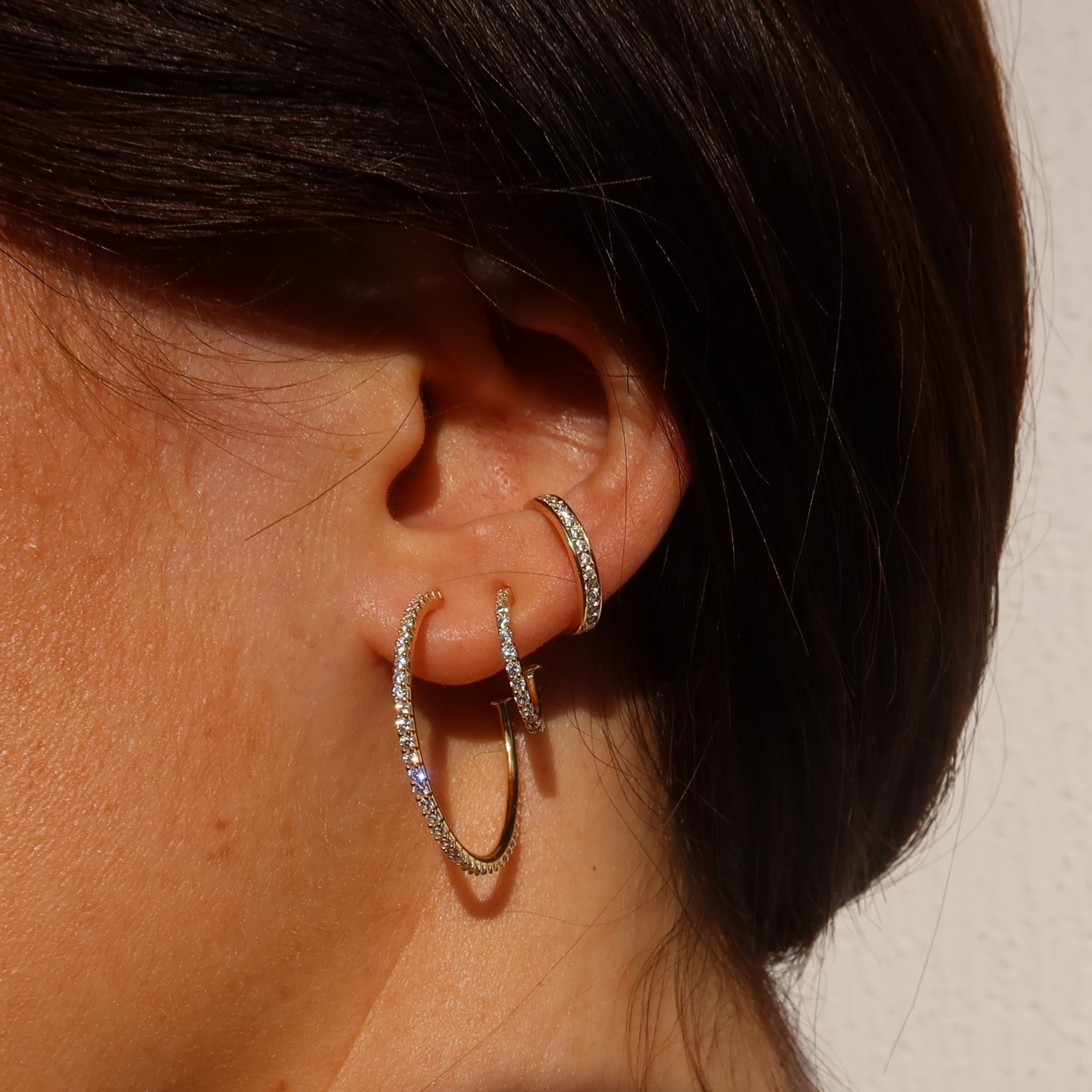Mehrere Zirkonia-Creolen in verschiedenen Größen am Ohr, eleganter Ear-Party-Look.